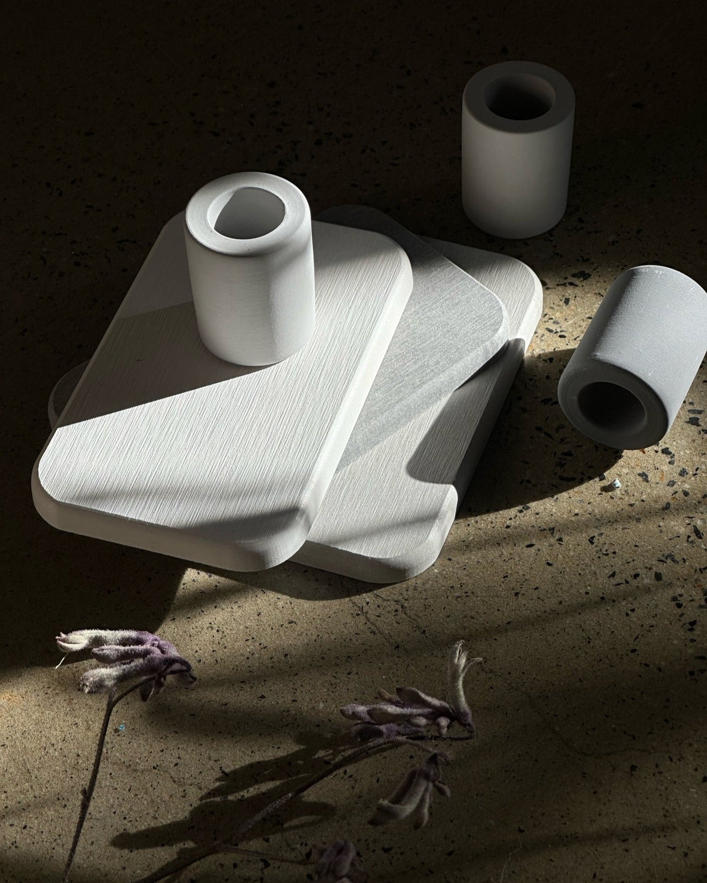 Minimalist diatomite toothbrush holders in light and dark grey styled on matching diatomite bathroom coasters